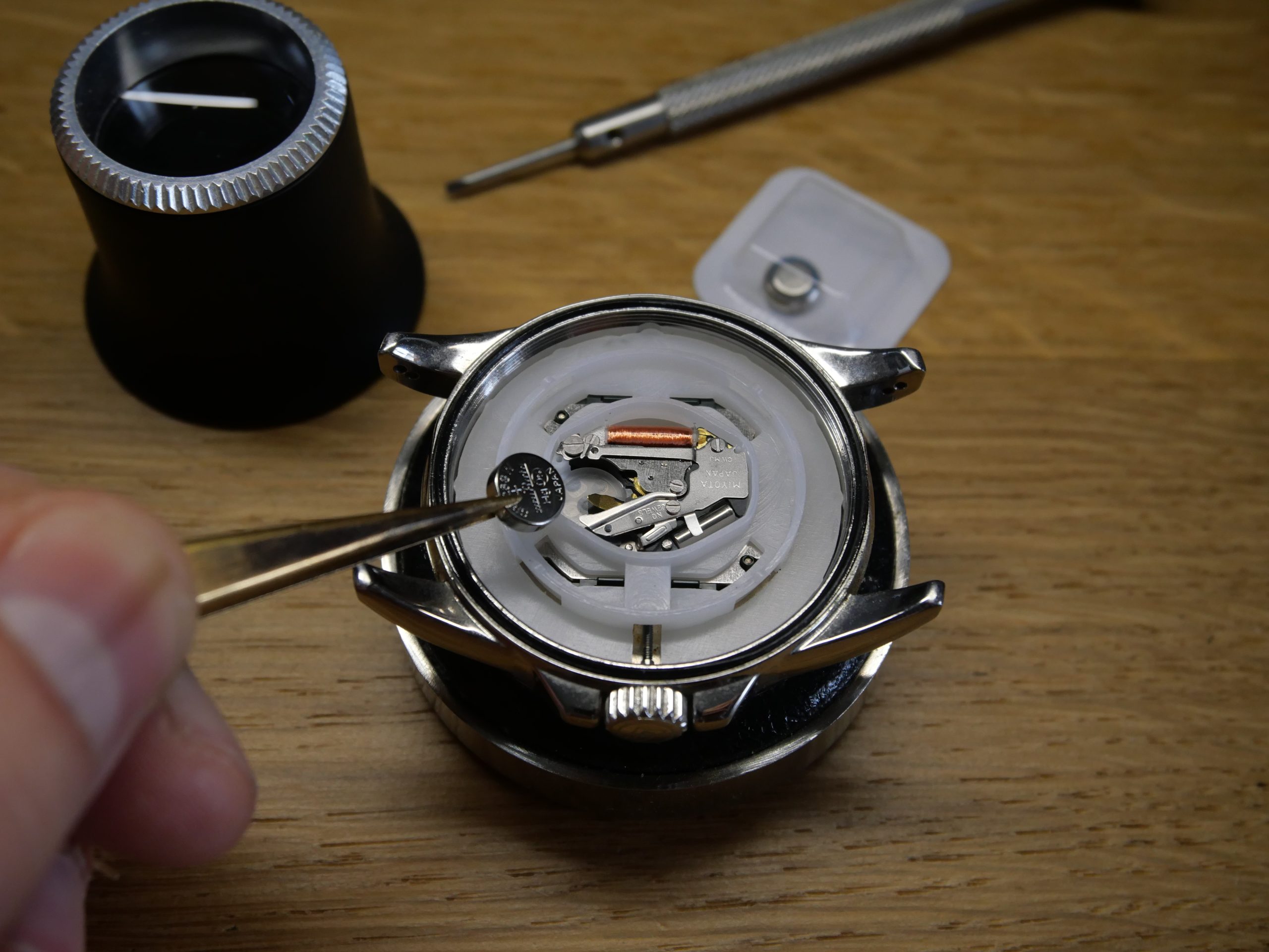 Changement de pile sur une montre à quartz, mouvement Miyota visible dans le boîtier ouvert